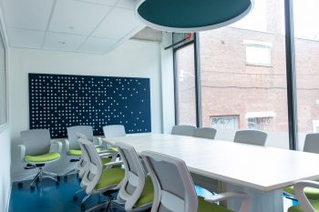 Large white table with 7 office chairs and large window.