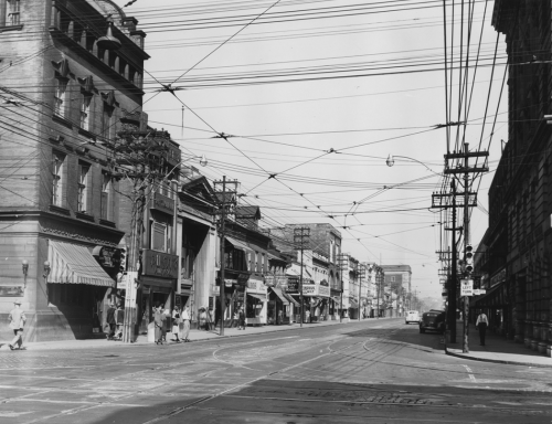 A street lined with stores of varying sizes and architectural styles.