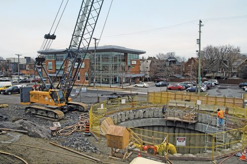 Photo of a large open circular shaft is surrounded by construction equipment