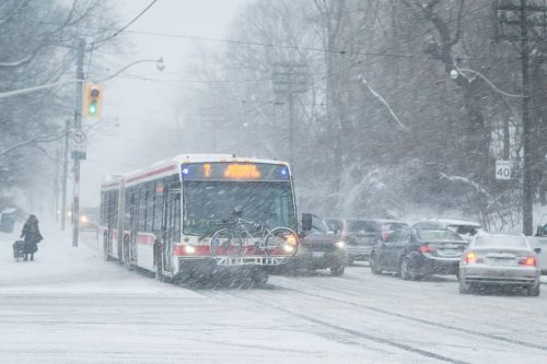 A TTC bus drives through a thick snowfall.