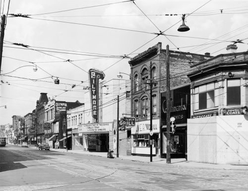 A line of stores and services include the Silver Grill, the Biltmore cinema, Continental Clothes, and a boarded-up building on the corner.