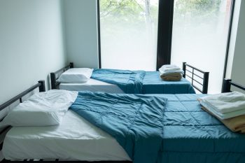 Two beds with blue covers and a large window.