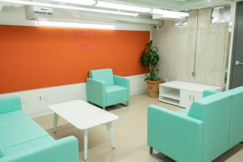 orange walls with three teal couches.