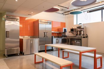 orange kitchen with industrial fridge and white picnic table