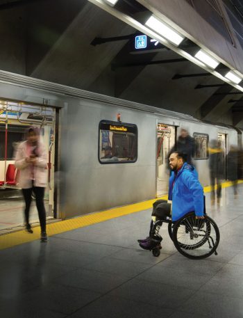 A man in a wheelchair waits to board a subway train.