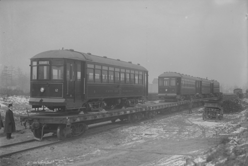 Two streetcars sitting on top of an open train car.