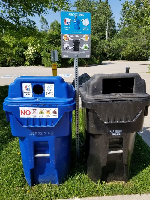 Beverage Bin with signage that reads Empty Cans and Empty Bottles beside a Garbage Bin