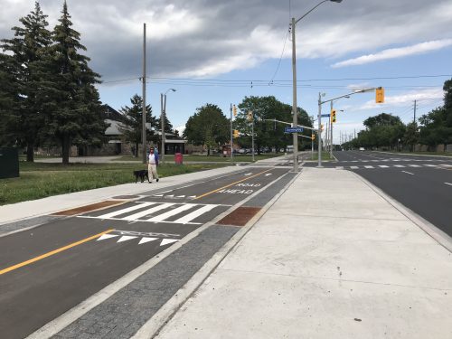 A multi-use trail is separated from motor vehicle traffic, and includes pavement markings and crossings for pedestrians.