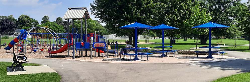 A photograph of Silver Creek Park taken on a sunny day. The park features mature trees throughout an open lawn area.