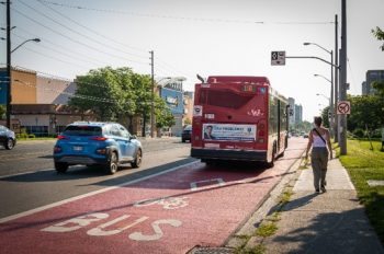 A bus travelling on the RapidTO: Eglinton East Bus Lanes identifed by the red pavement paint and markings.