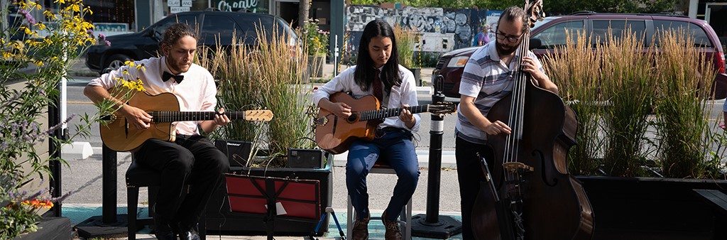 Local band of three people performing live music on a cafe patio.