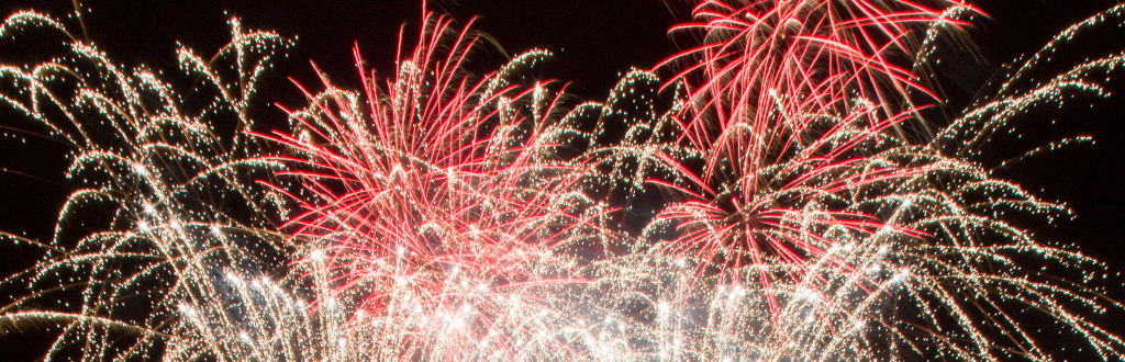 Gold and red fireworks going off in front of a black sky