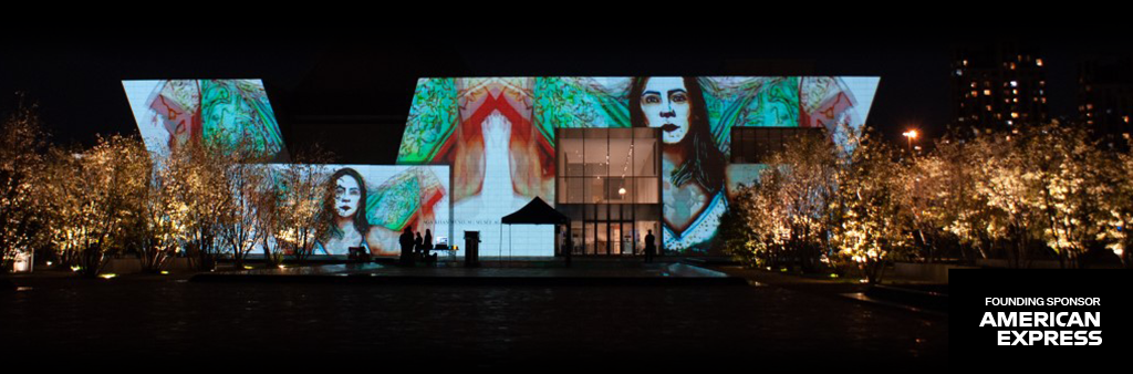 Building lit up with art projection at night, founding sponsor American Express