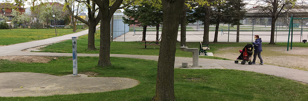 An image of the existing splash pad in Pelmo Park, which is surrounded by grass, trees and various pathways. The splash bad is concrete and small in size.