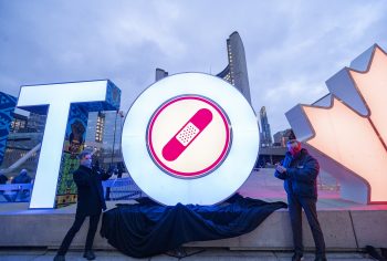 Councillor Joe Cressy and Mayor John Tory unveil the new Team Toronto pink bandage added to Toronto Sign. In the backdrop is City Hall.