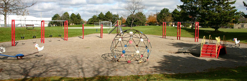 A photograph of the playground in L'Amoreaux Park which includes various stand-alone play structures and features in the foreground.