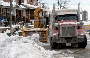 Heavy machinery moves snow into dump truck