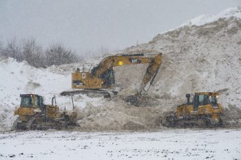 heavy machinery make space for more snow at the snow storage site