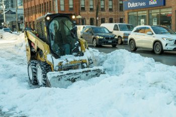 skid steer loader moves snow in bike lane
