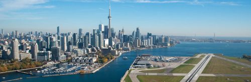 Aerial view of Bill Bishop Toronto city airport terminal looking East, with CN Tower and sail boats and financial district.