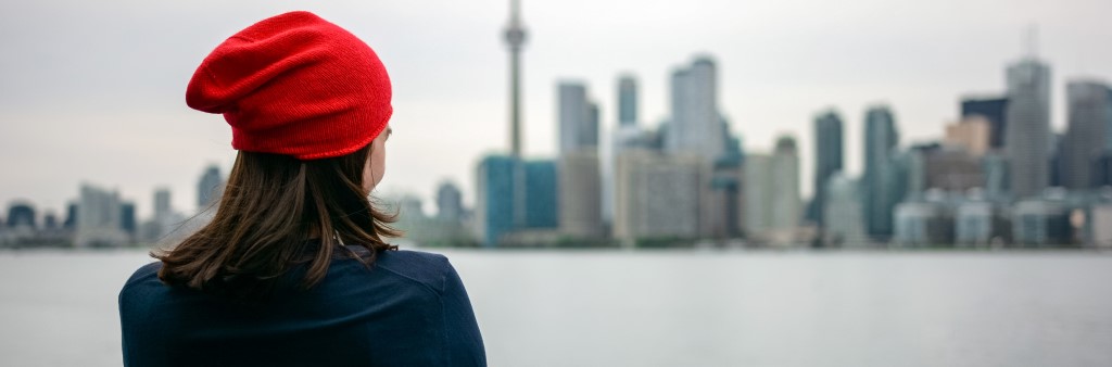 Woman looks across water onto Toronto skyline in winer