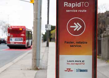 Toronto street view showing a transit bus and sign promoting the RapitTO campaign.