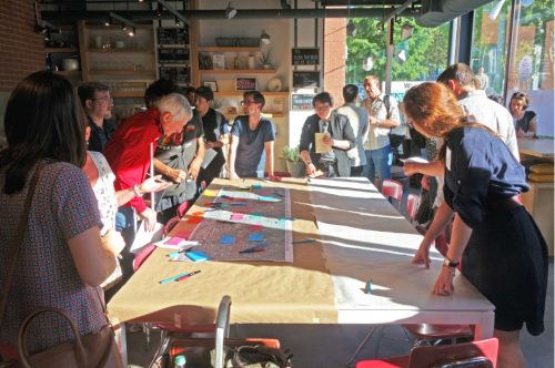 Community members gather around a table at a public open house for the West Queen West Heritage Conservation District Study