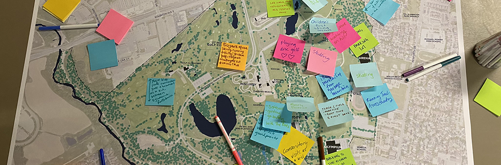 Map of Centennial Park sits on a table with sticky notes and markers scattered across it. Sticky notes contain handwritten comments and ideas from workshop participants on how Centennial Park can be improved.