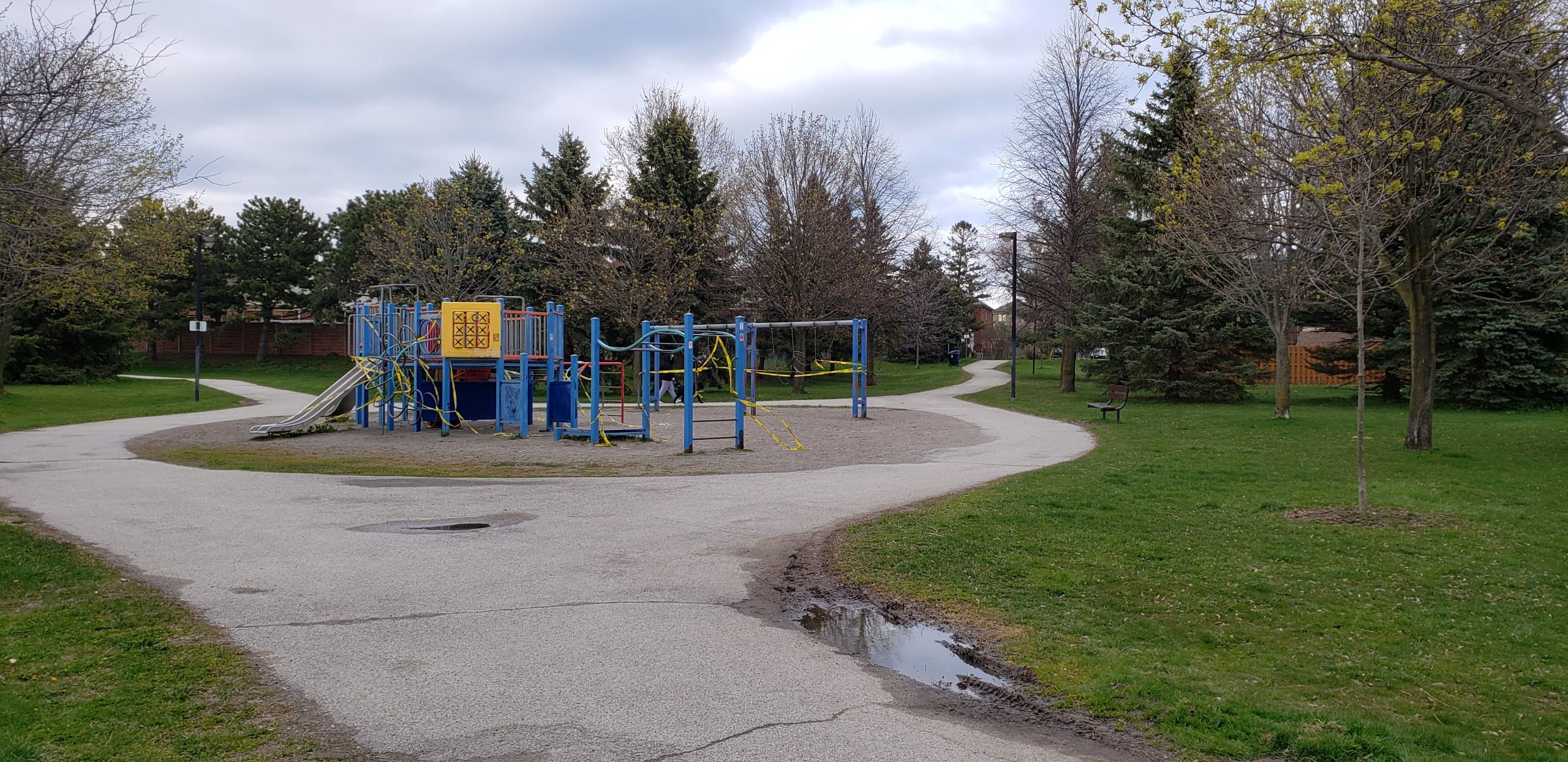Old play equipment at Natal Park includes blue climbing structure with metal slide and monkey bars, and a swing set on a gravel play surface.