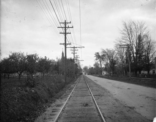 View of rail track, unpaved road and hydro lines.