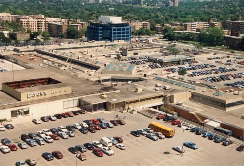 Overhead view of shopping complex with parking lot and cars in foreground. Visible on the building is a sign that says Eaton's.