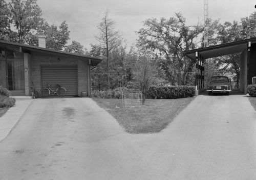 View of split driveway leading to two bungalows. Garage on left, car port on right.