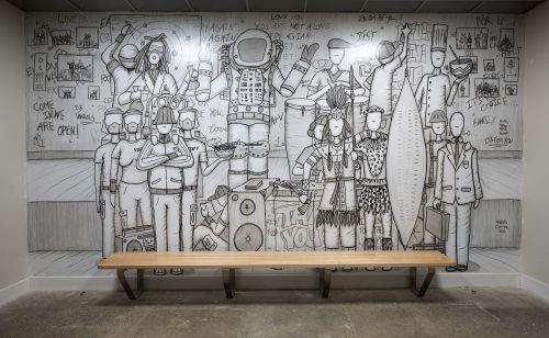 monochromatic mural of people with bench in foreground