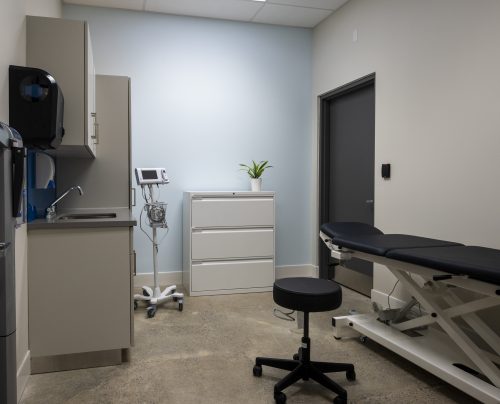 Doctor's office with adjustable height bed, stool, chest of drawers, sink and medical equipment