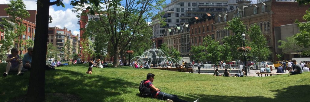 Photo of Berzy Park, many people sitting on the grass enjoying the weather.