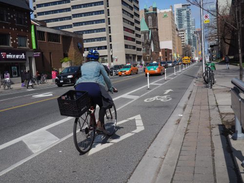 A person cycles in a cycle track with bollards in the buffers