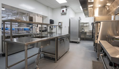industrial kitchen with stainless steel counters and appliances, opening to service window