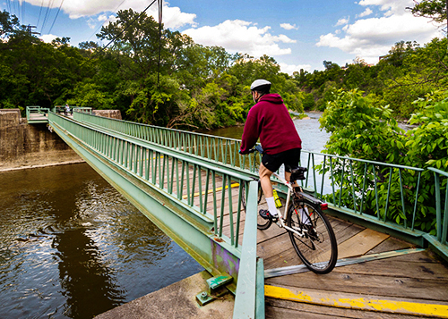 Person riding a bike on a bridge over the Humber River in Lambton Woods.