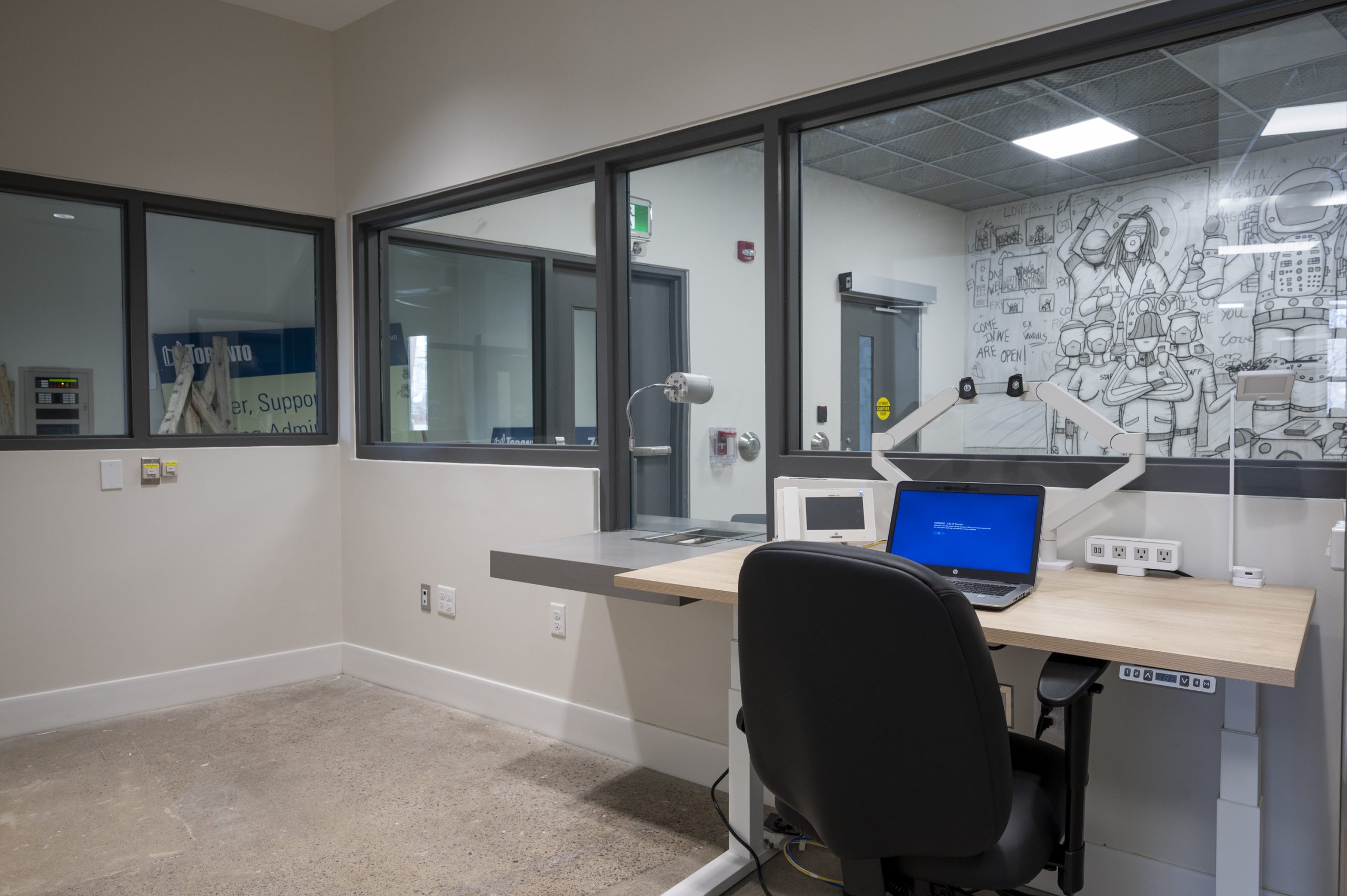 laptop, desk and chair in front of a service window