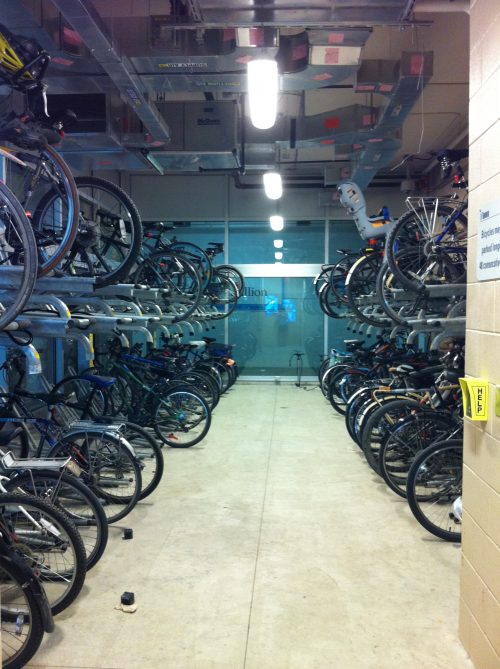 Bicycles are stored on two levels of racks in a secure parking station.