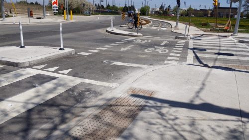 A person on a bike waits behind a corner island at a protected intersection. 