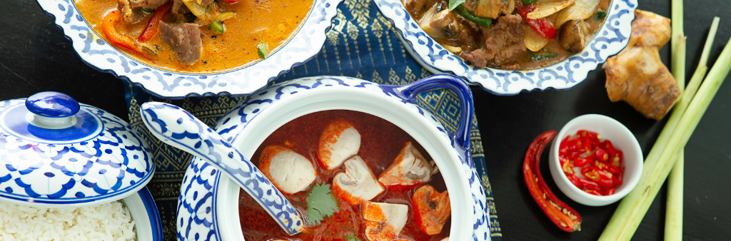 Bowls of Thai food, including soup and other dishes in colourful broth.