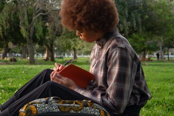 Woman sits in a park reading a book