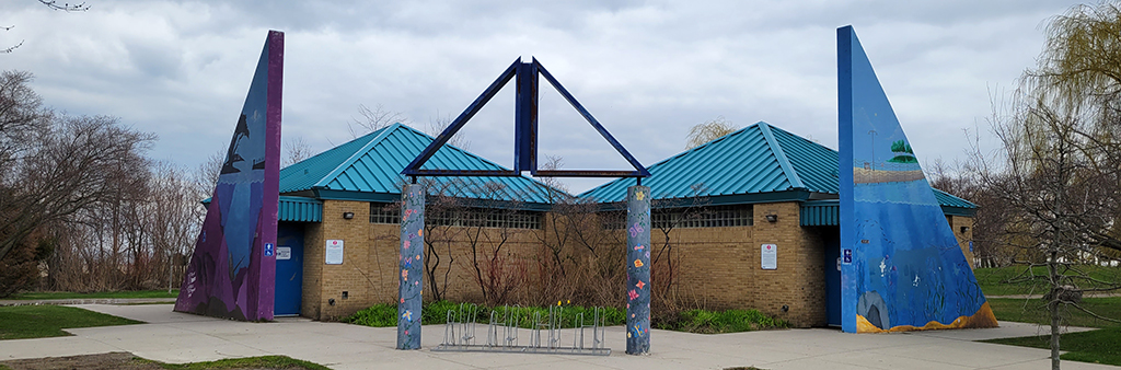 A brown brick building with a blue roof. A bicycle rack sits in front.