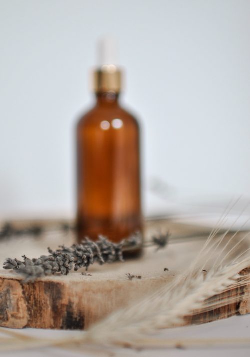 Bottle and lavendar sprig sitting on wood 