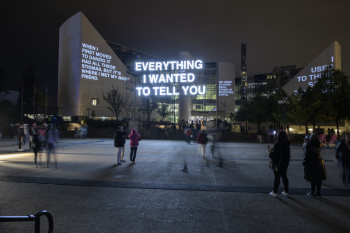 Light projection onto building with people watching and walking by