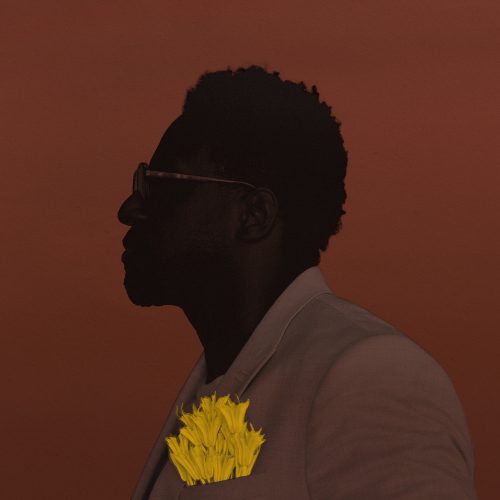 Portrait of a man wearing sunglasses and a white suit jacket with a yellow flower in the breast pocket