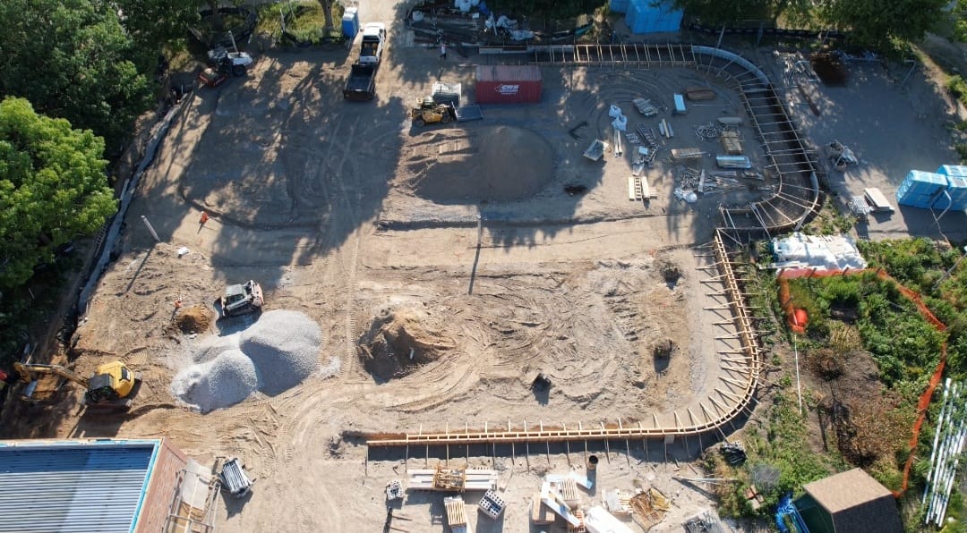 Aerial view of rink and pleasure pad construction showing wooden formwork framing the boundaries of the rink and pleasure pad. Construction equipment and material can be seen throughout the site.
