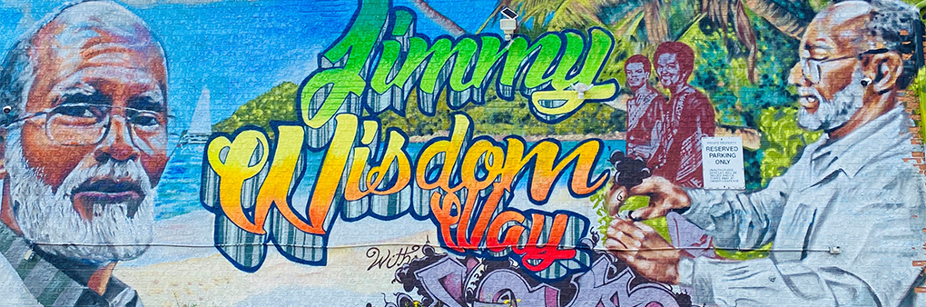 Mural of Jimmy Wisdom at an older age on the far left, with the words "Jimmy Simpson Way" in the middle. On the far right are a few portraits of Wisdom at different ages, with the island of Jamaica in the background.