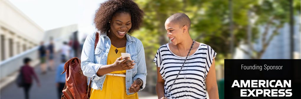 Two women walking together and looking at a mobile phone